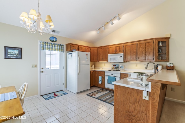 kitchen featuring white appliances, vaulted ceiling, track lighting, a peninsula, and light countertops