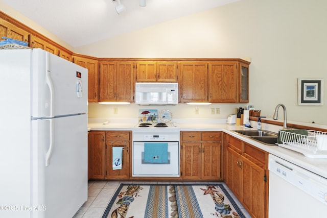 kitchen featuring white appliances, lofted ceiling, a sink, brown cabinetry, and light tile patterned floors