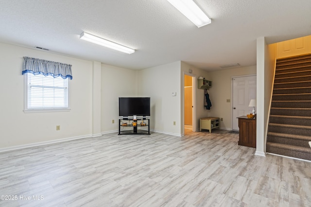 unfurnished living room featuring a textured ceiling, stairway, light wood-type flooring, and baseboards