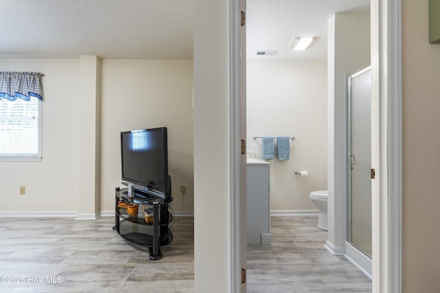 full bath with wood finished floors, a stall shower, toilet, a textured ceiling, and baseboards
