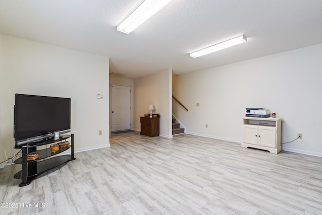 unfurnished living room featuring stairs, light wood-style flooring, and baseboards