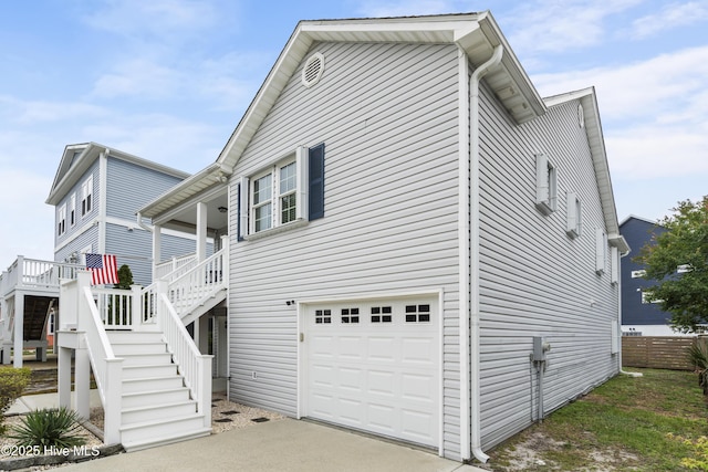 view of side of home featuring a garage, stairway, driveway, and fence
