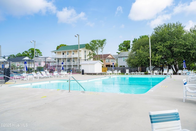 community pool featuring fence, a patio, and a residential view