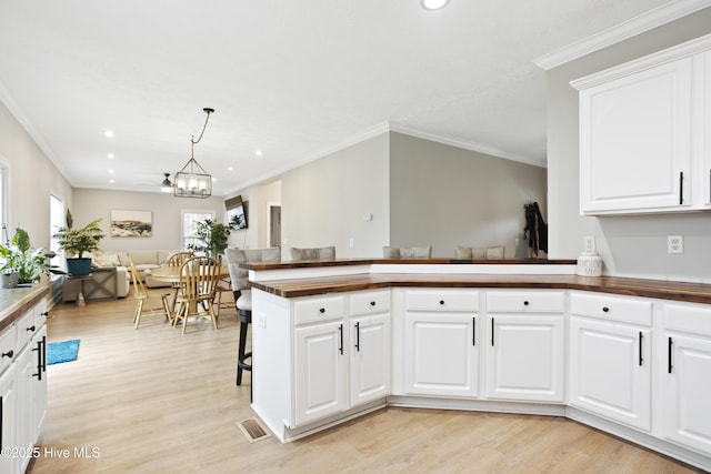 kitchen featuring light wood-type flooring, open floor plan, ornamental molding, recessed lighting, and a chandelier