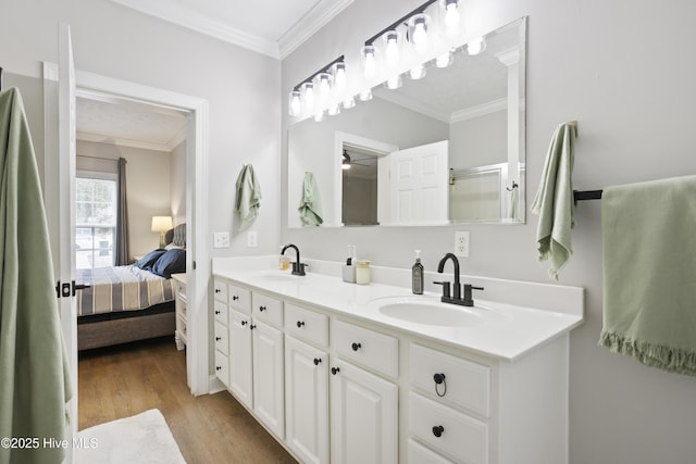bathroom featuring ornamental molding, ensuite bath, wood finished floors, and double vanity