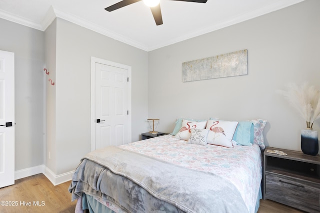 bedroom with wood finished floors, crown molding, baseboards, and ceiling fan