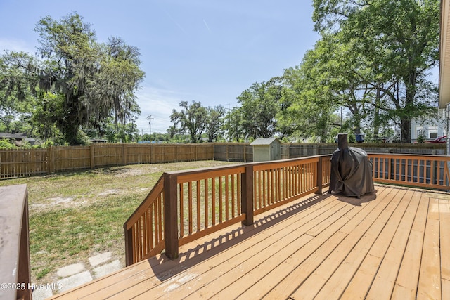 deck with a storage shed, an outdoor structure, and a grill
