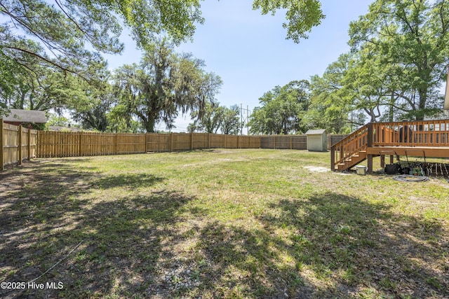 view of yard featuring a storage shed, a wooden deck, and an outbuilding