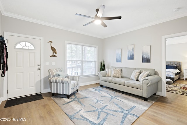 living area with wood finished floors, crown molding, ceiling fan, and baseboards