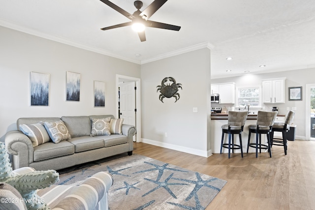 living area featuring baseboards, light wood finished floors, crown molding, a ceiling fan, and recessed lighting