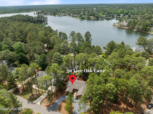 aerial view of property and surrounding area featuring a heavily wooded area and a large body of water