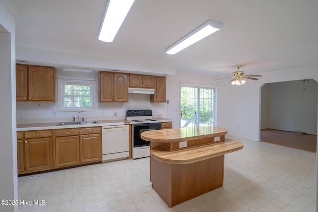 kitchen featuring white appliances, a sink, light flooring, light countertops, and under cabinet range hood