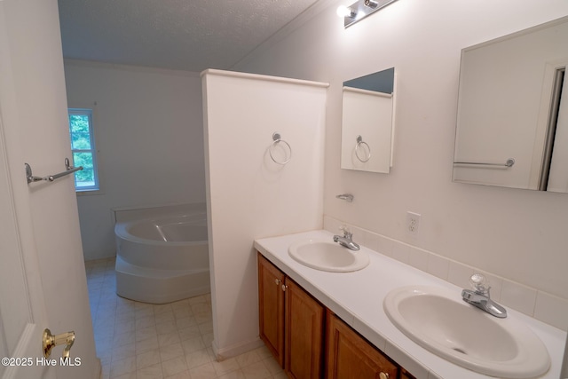 full bath with a bath, double vanity, and a textured ceiling