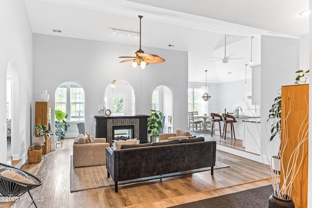 living area featuring a ceiling fan, wood finished floors, healthy amount of natural light, and a towering ceiling