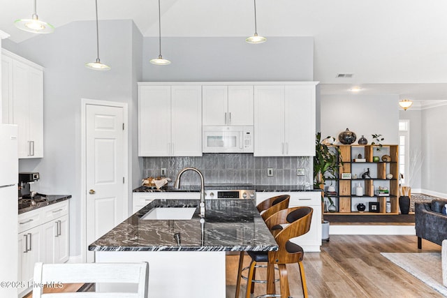 kitchen with white appliances, a sink, light wood-style flooring, high vaulted ceiling, and white cabinetry