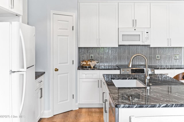 kitchen with white appliances, decorative backsplash, light wood finished floors, and white cabinetry