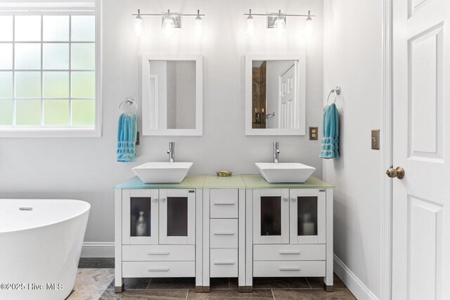 full bath with double vanity, a freestanding tub, and baseboards