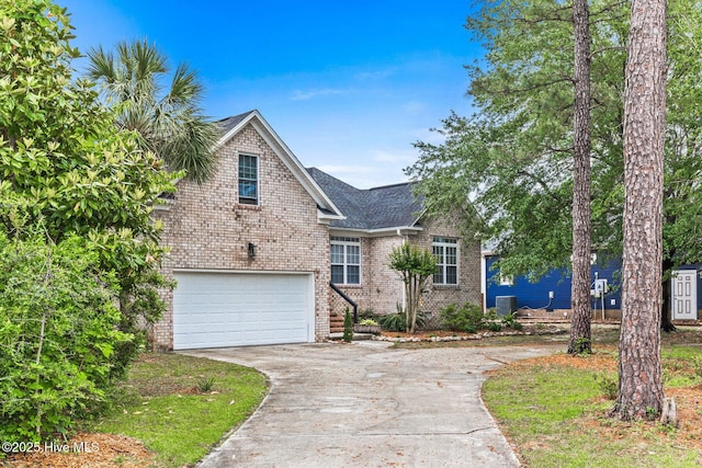 traditional-style house featuring driveway, brick siding, an attached garage, central air condition unit, and a shingled roof