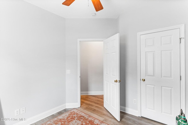 unfurnished bedroom featuring wood finished floors, baseboards, and a ceiling fan