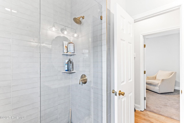 full bath featuring a tile shower, wood finished floors, and baseboards