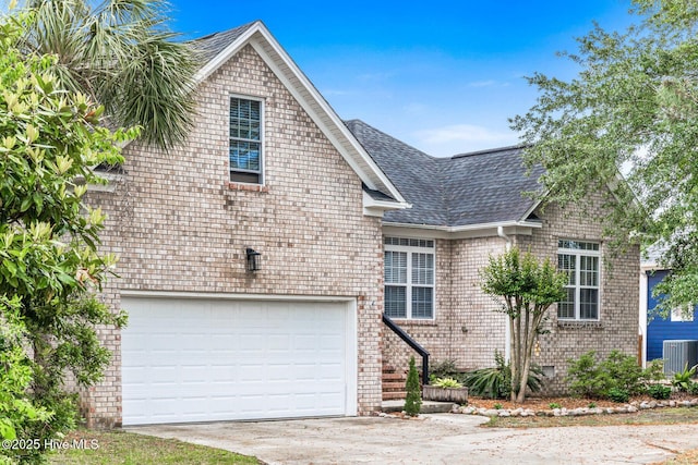 view of front of property featuring a shingled roof, concrete driveway, central AC unit, an attached garage, and brick siding