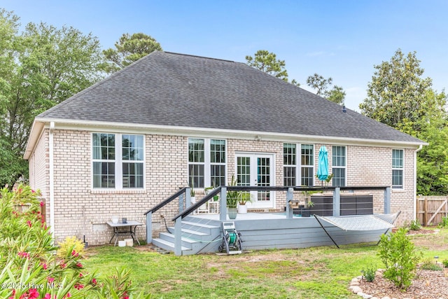 back of property featuring brick siding, a deck, and roof with shingles