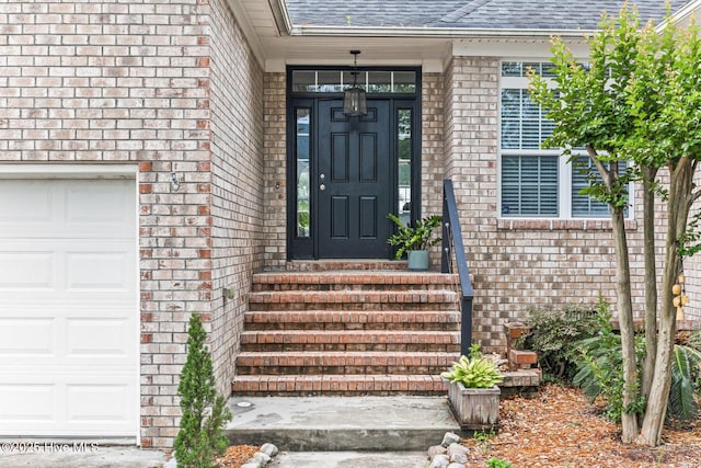 entrance to property featuring brick siding, roof with shingles, and a garage