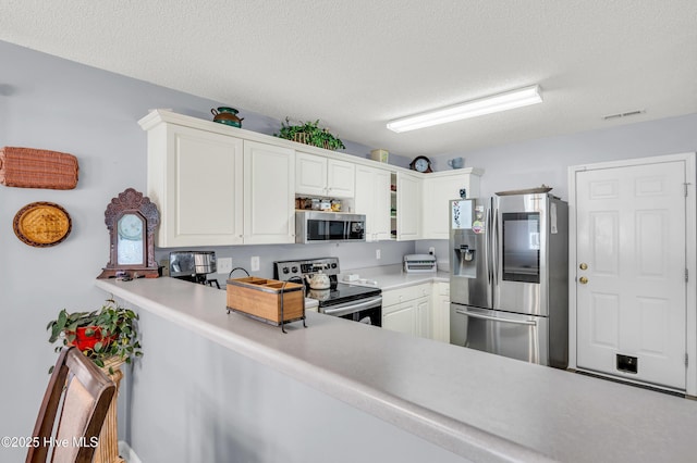 kitchen with stainless steel appliances, white cabinetry, light countertops, and a textured ceiling