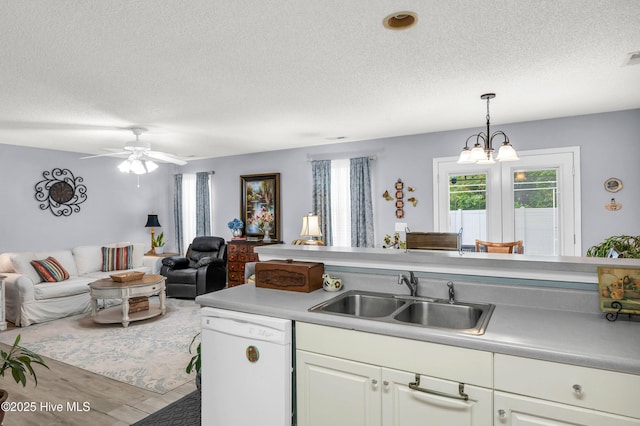 kitchen featuring dishwasher, a sink, a textured ceiling, open floor plan, and light countertops