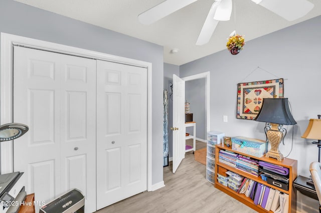 office space with light wood-type flooring, ceiling fan, and baseboards