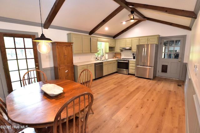 kitchen featuring stainless steel appliances, under cabinet range hood, a sink, light countertops, and decorative backsplash