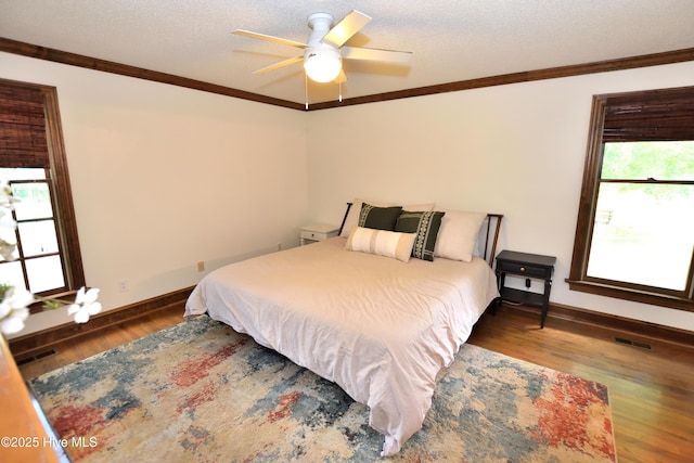 bedroom with crown molding, wood finished floors, baseboards, a ceiling fan, and a textured ceiling