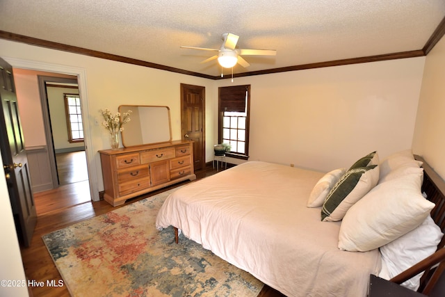 bedroom featuring multiple windows, wood finished floors, crown molding, a textured ceiling, and ceiling fan