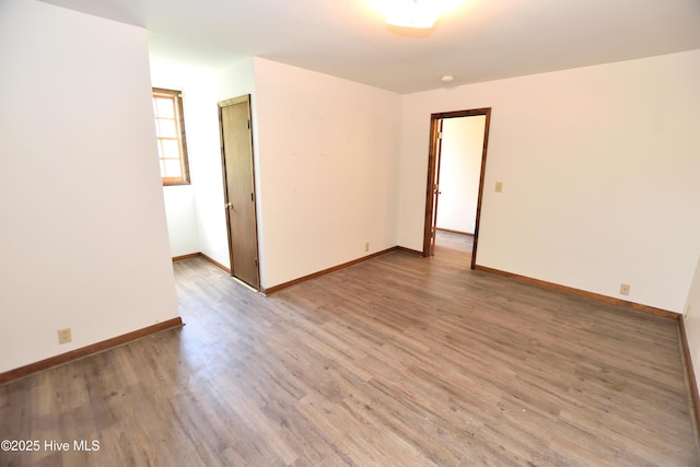 empty room featuring light wood finished floors and baseboards