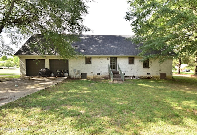 rear view of house with crawl space, a garage, concrete driveway, a lawn, and roof with shingles