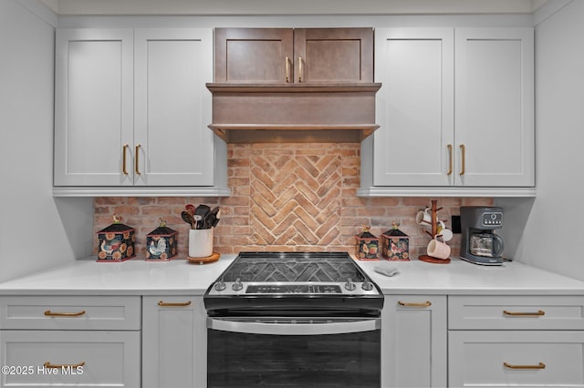 kitchen featuring range with electric stovetop, light countertops, decorative backsplash, and premium range hood