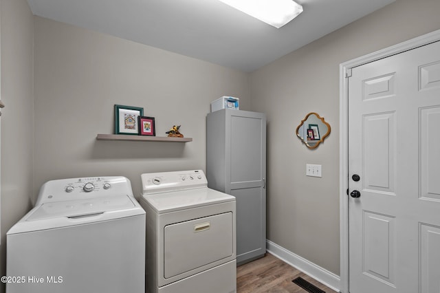 washroom with washer and dryer, light wood finished floors, cabinet space, and baseboards