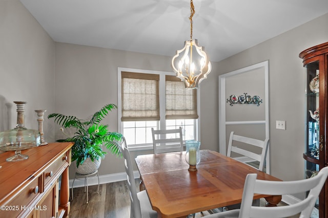 dining space featuring a chandelier, dark wood-style flooring, and baseboards