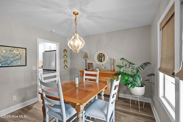 dining space with baseboards, wood finished floors, and a chandelier