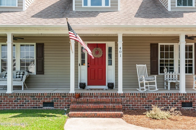 view of exterior entry with covered porch and roof with shingles