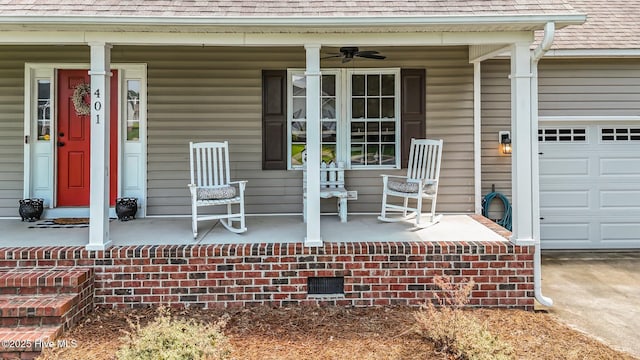 view of exterior entry with a porch, a shingled roof, a garage, a ceiling fan, and concrete driveway