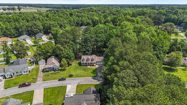 aerial view of property and surrounding area featuring a forest and nearby suburban area