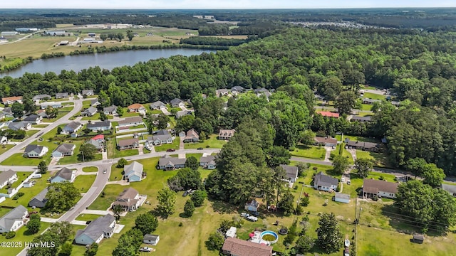 view of property location featuring a large body of water, a forest, and nearby suburban area