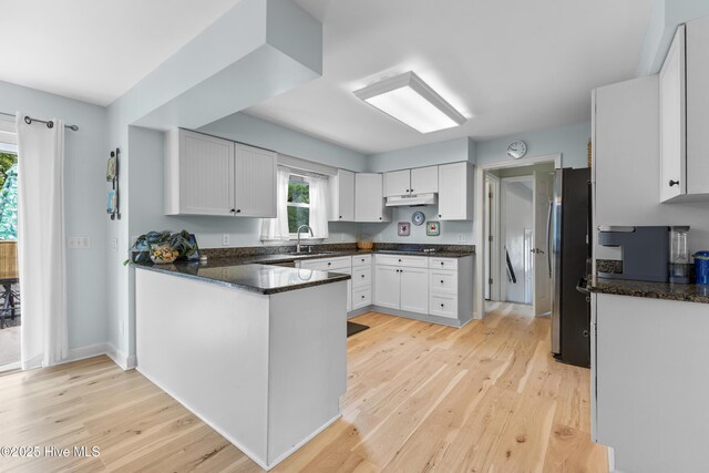 209 Inlet Dr, Wilmington, NC 28411 - kitchen featuring freestanding refrigerator, a sink, light wood finished floors, a peninsula, and white cabinets