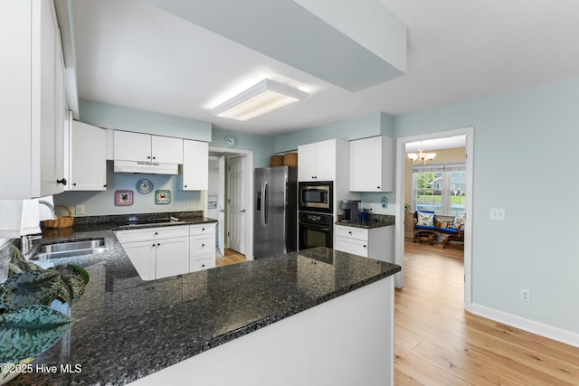 209 Inlet Dr, Wilmington, NC 28411 - kitchen with black appliances, under cabinet range hood, a sink, a chandelier, and light wood-type flooring