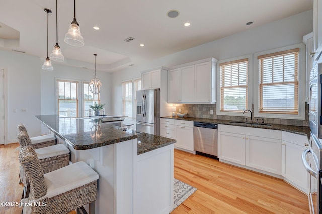 353 Spicer Lake Dr, Holly Ridge, NC 28445 - kitchen featuring appliances with stainless steel finishes, a sink, light wood finished floors, a kitchen bar, and white cabinets