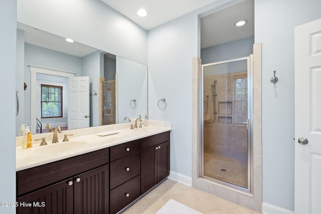 full bathroom featuring a shower stall, double vanity, baseboards, tile patterned floors, and recessed lighting