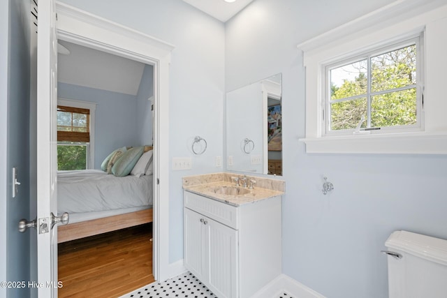 bathroom with ensuite bathroom, plenty of natural light, vanity, and toilet
