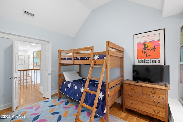 bedroom featuring wood finished floors and lofted ceiling