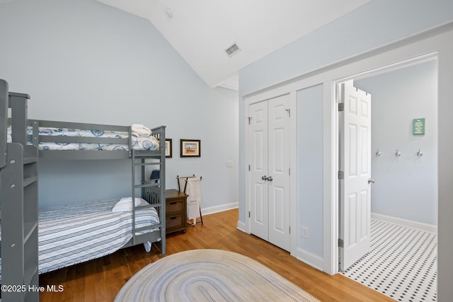 bedroom with wood finished floors, lofted ceiling, and baseboards